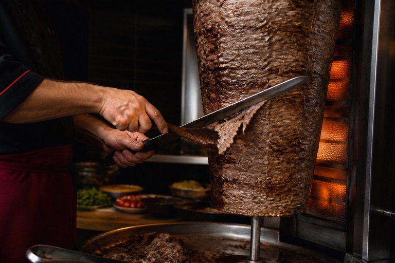 Döner ocağında et kesen deneyimli usta eller