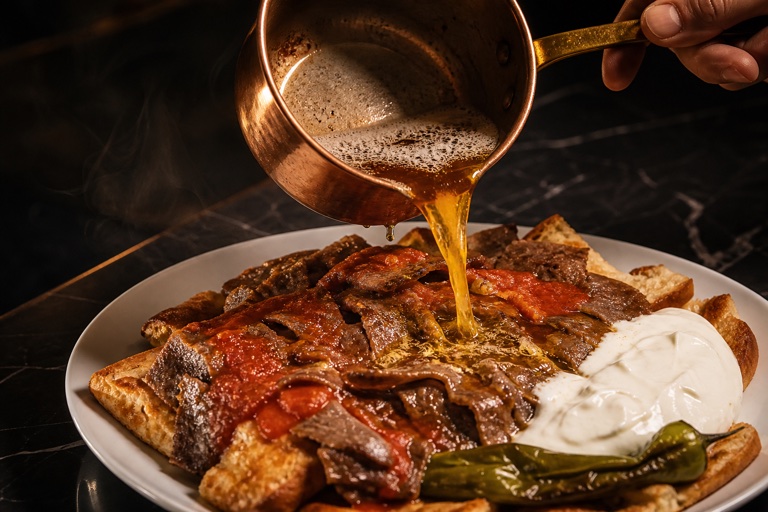 Pide tabanında domates sosu ve yoğurtla servis edilen İskender